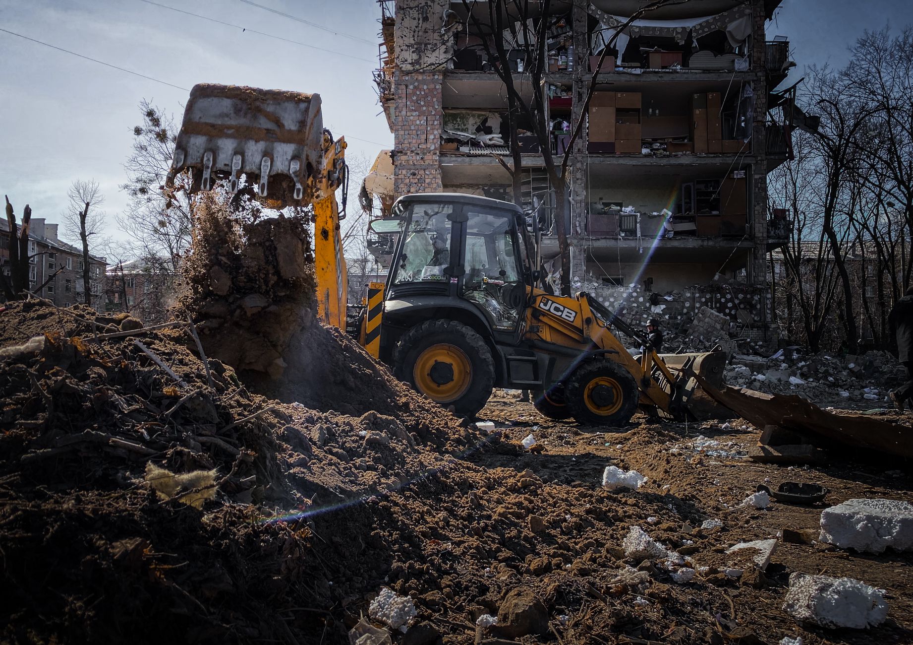 Excavator demolishing a building in Kyiv, Ukraine amidst rubble and debris.