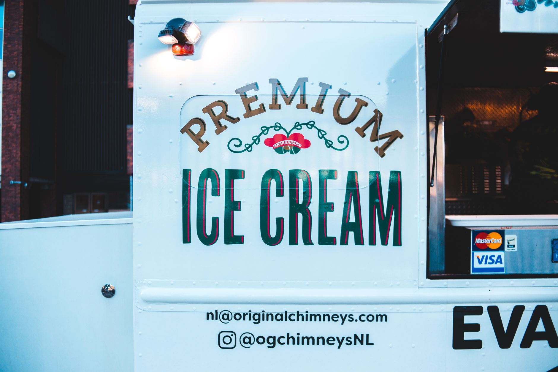 Close-up of a branded ice cream truck featuring payment stickers and vibrant signage.
