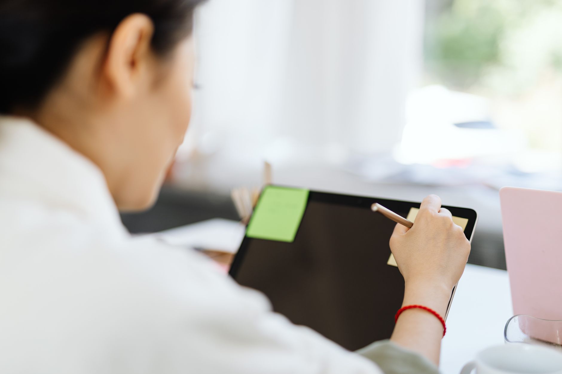 A woman using a stylus on a tablet in a modern office setting.