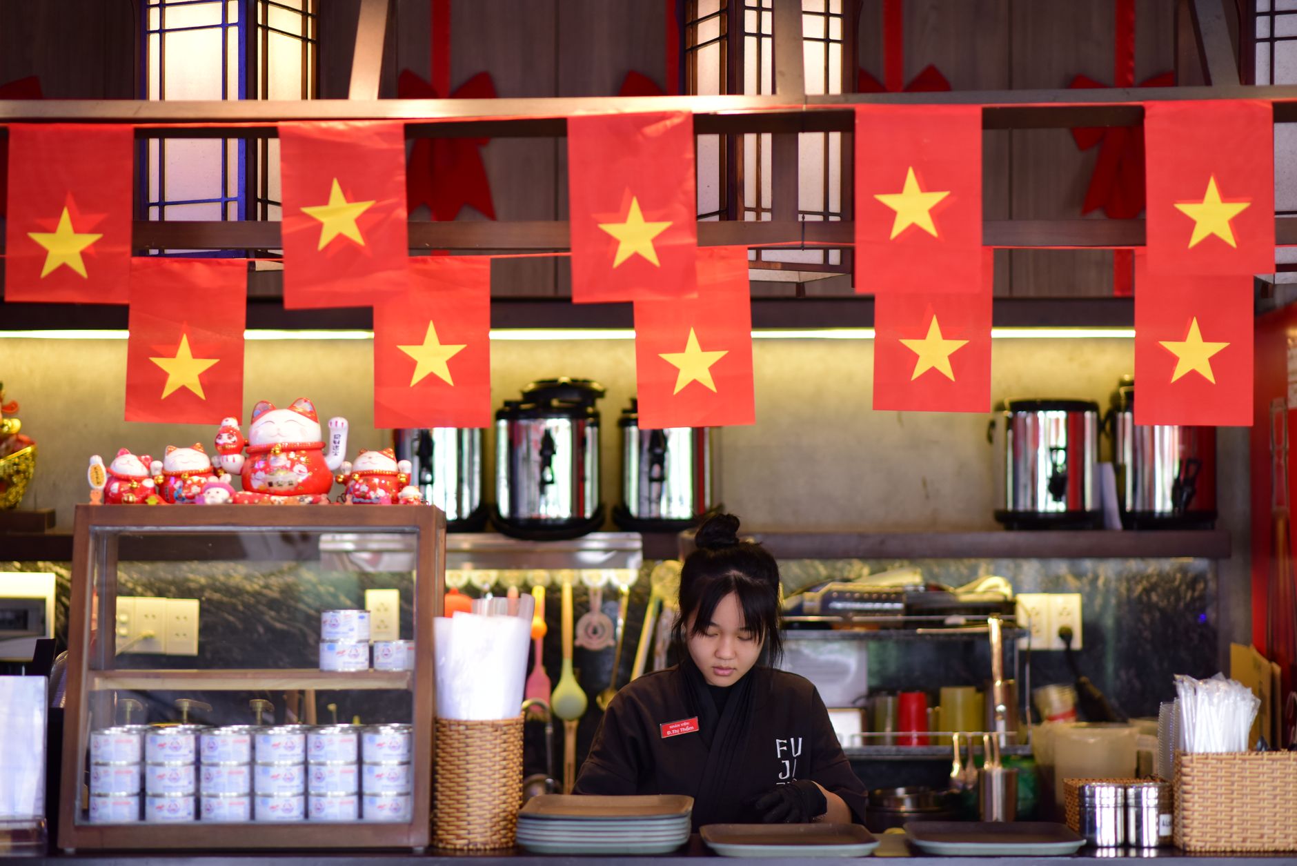 Vibrant Vietnamese restaurant interior featuring national flags and attentive staff member at the counter.