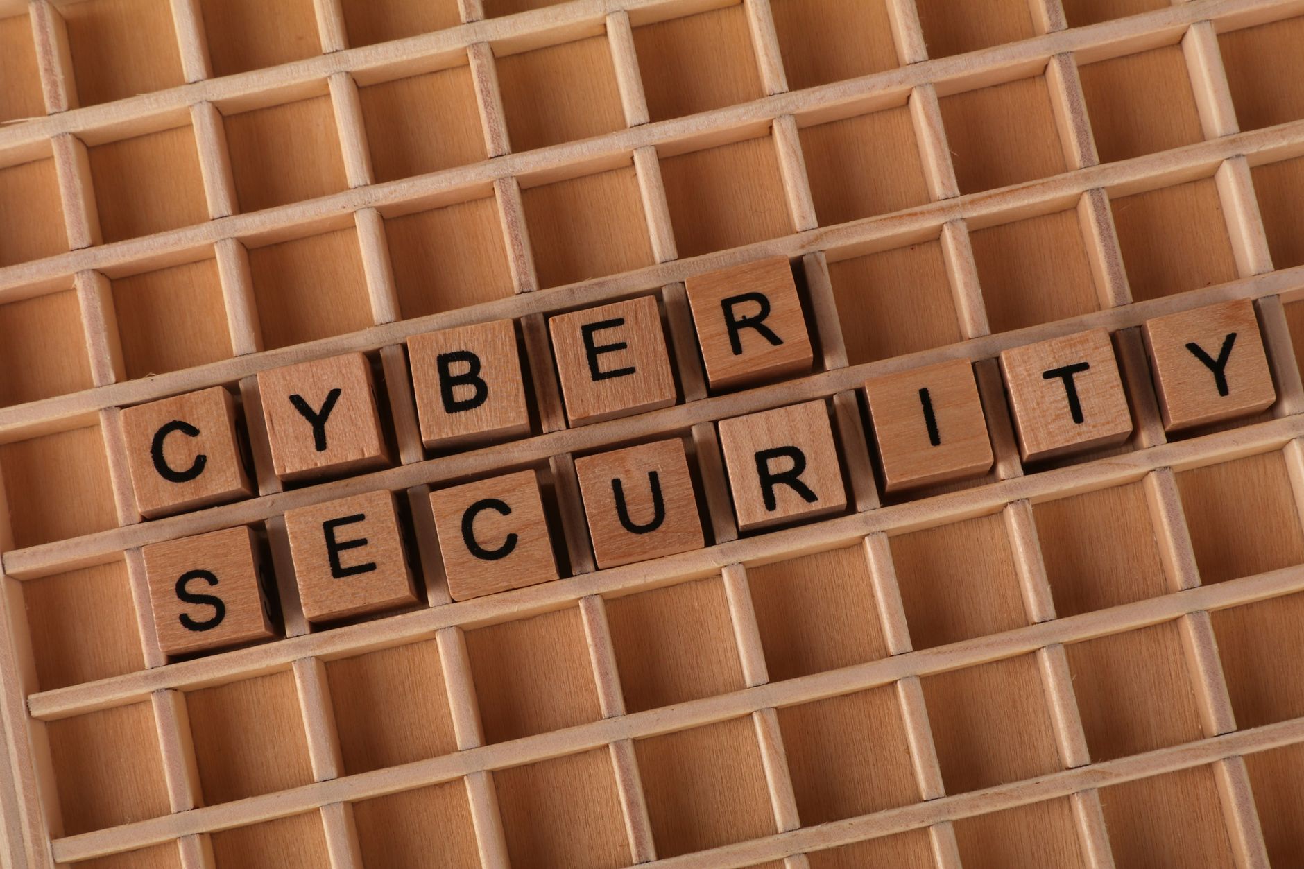 Wooden blocks spelling 'Cyber Security' on a wooden grid background.