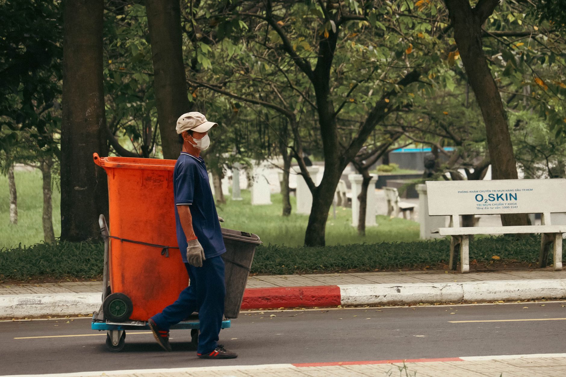 A street worker collects trash in a park, emphasizing urban cleanliness.