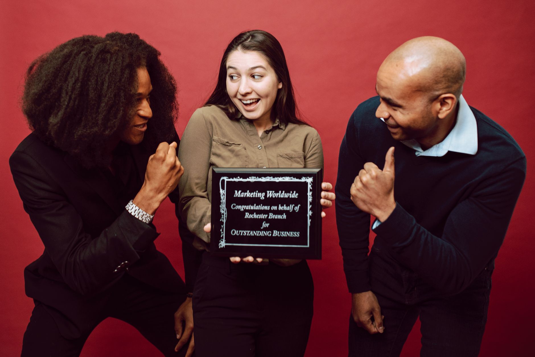 Diverse team celebrating with an achievement plaque and cheerful expressions.