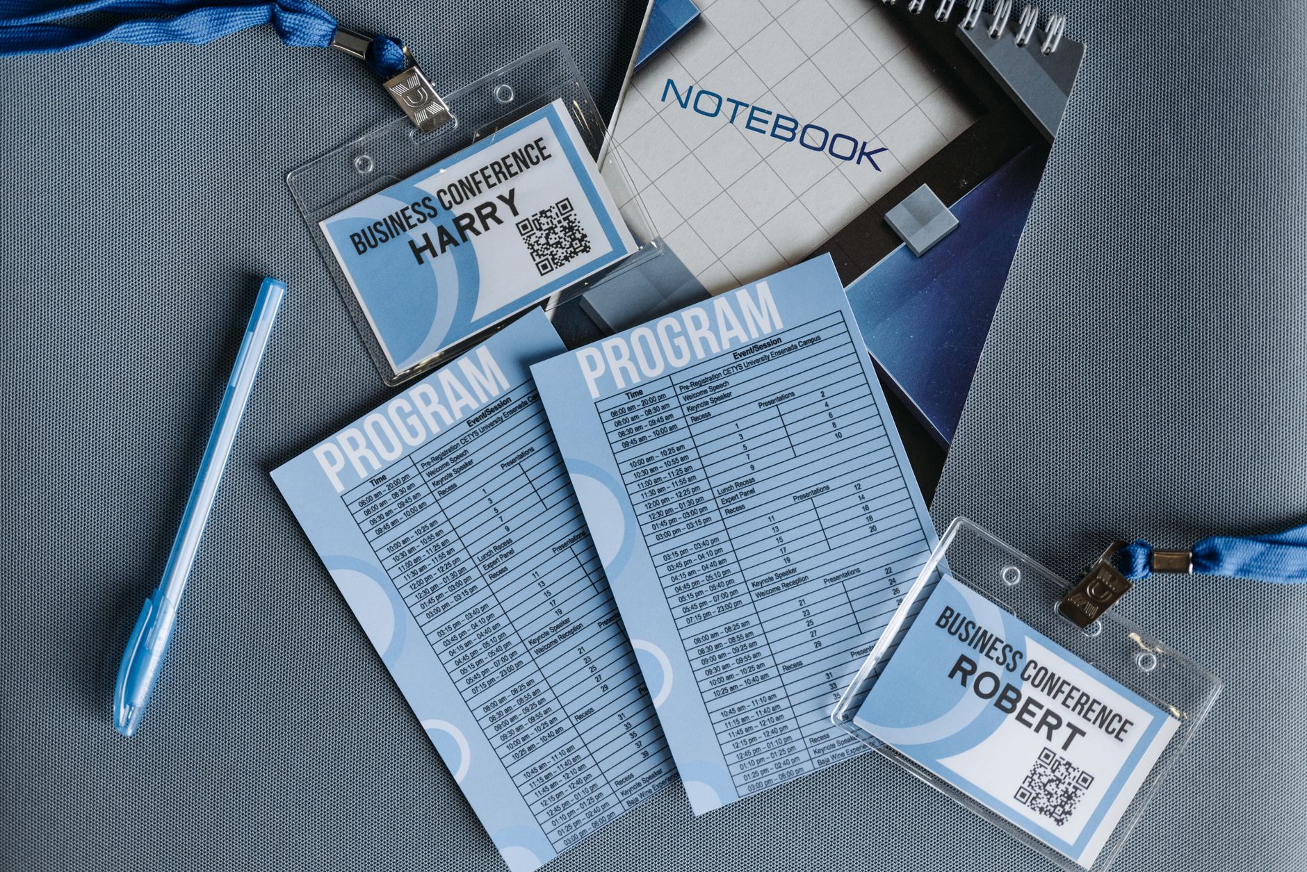 Flat lay of business conference materials including name tags, program, notebook, and pen.