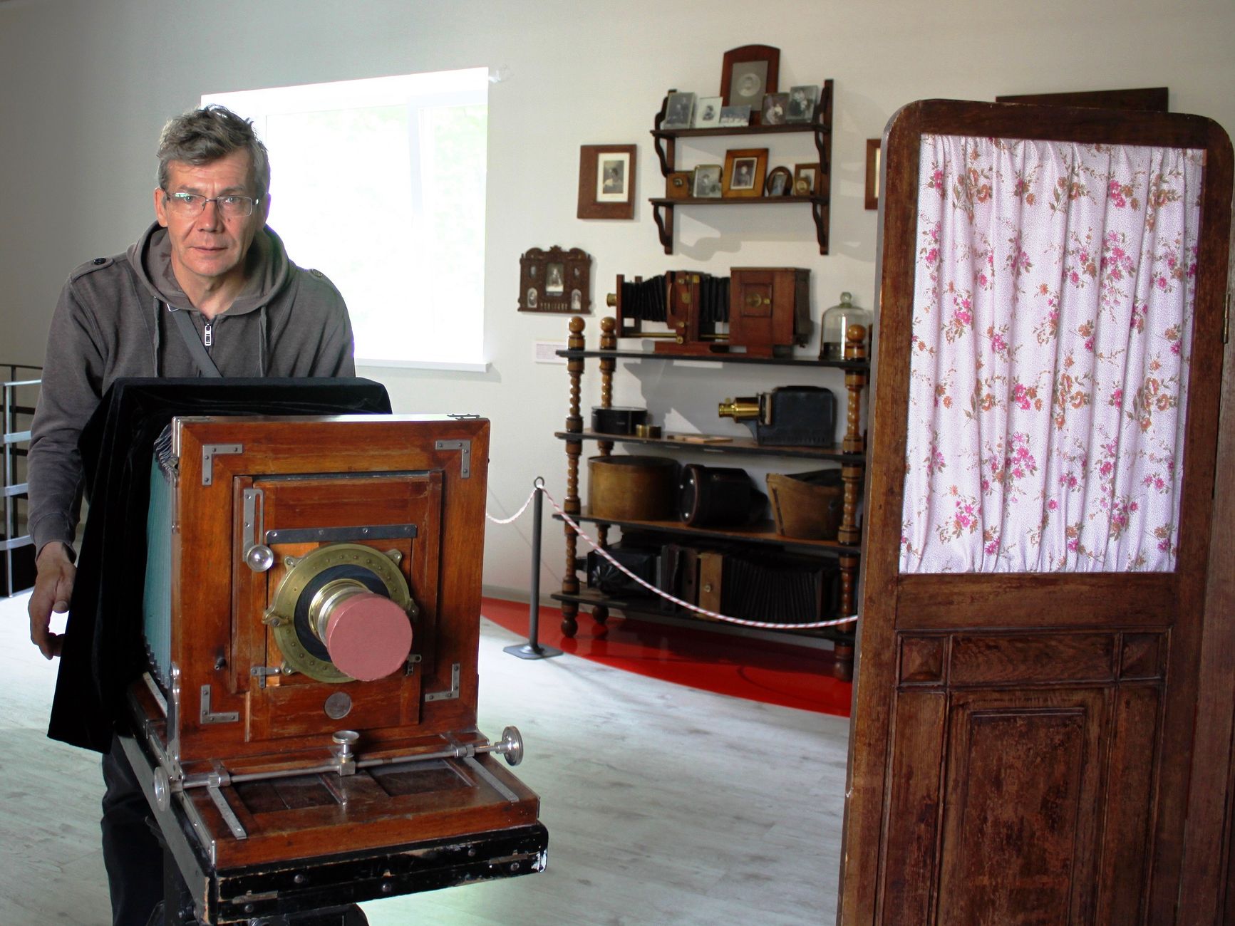 An older man operates a vintage large format camera in a classic photography studio.
