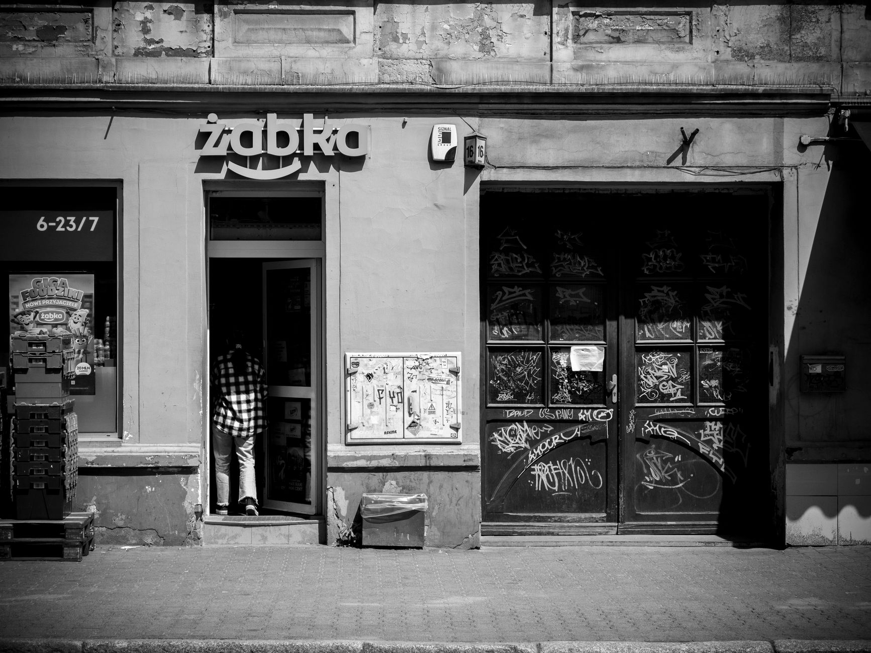 A captivating black and white photo of a Żabka store exterior in Wrocław, Poland, capturing urban street life.