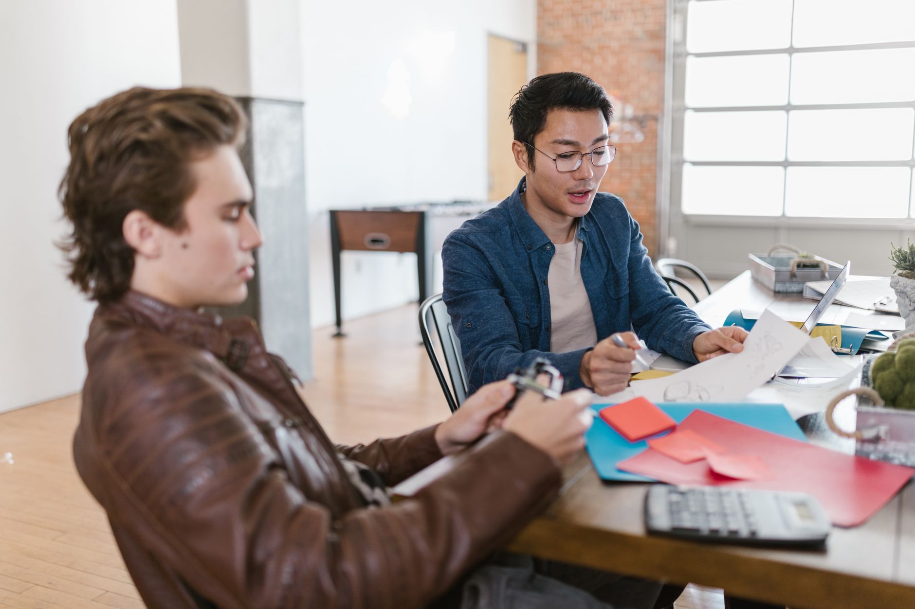Two young entrepreneurs brainstorm ideas in a modern office setting, fostering innovation and collaboration.