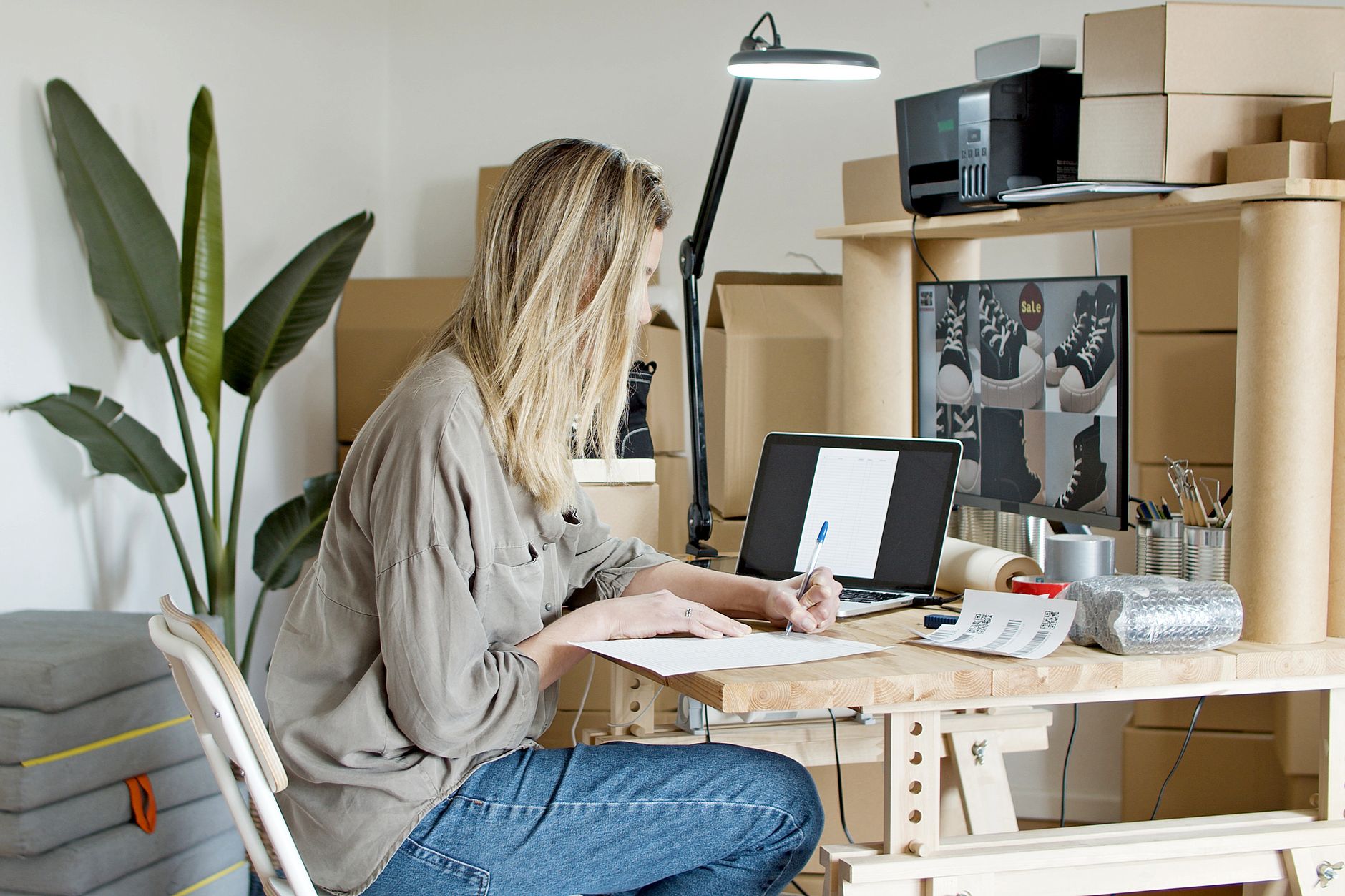 A young woman managing her online store startup, working diligently from her home office in Portugal.