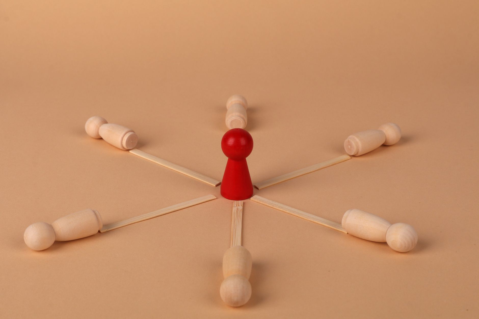 Red leader figure connected to wooden figures, emphasizing leadership and teamwork.