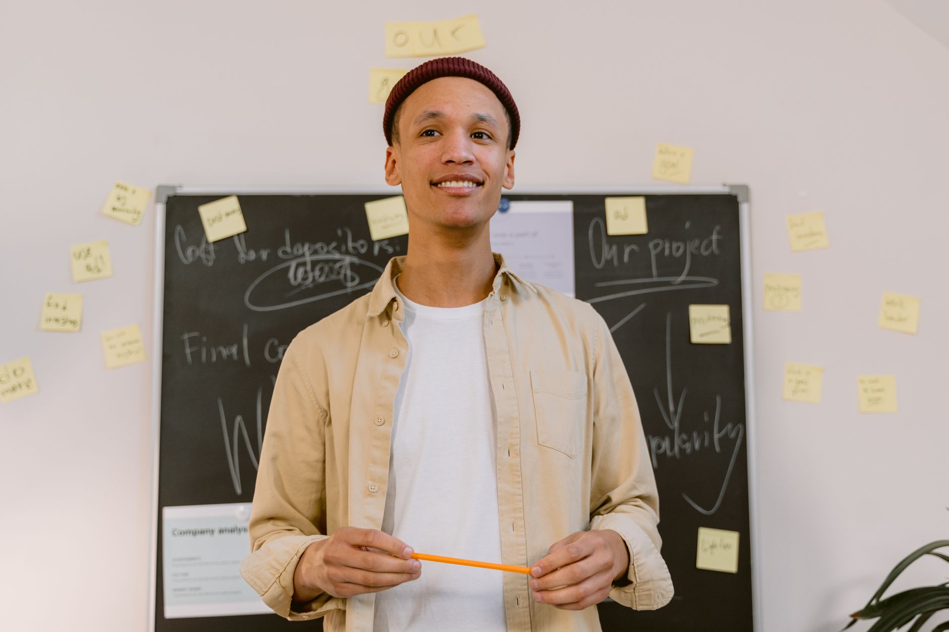 Confident young man smiling while leading a presentation in a modern office setting.