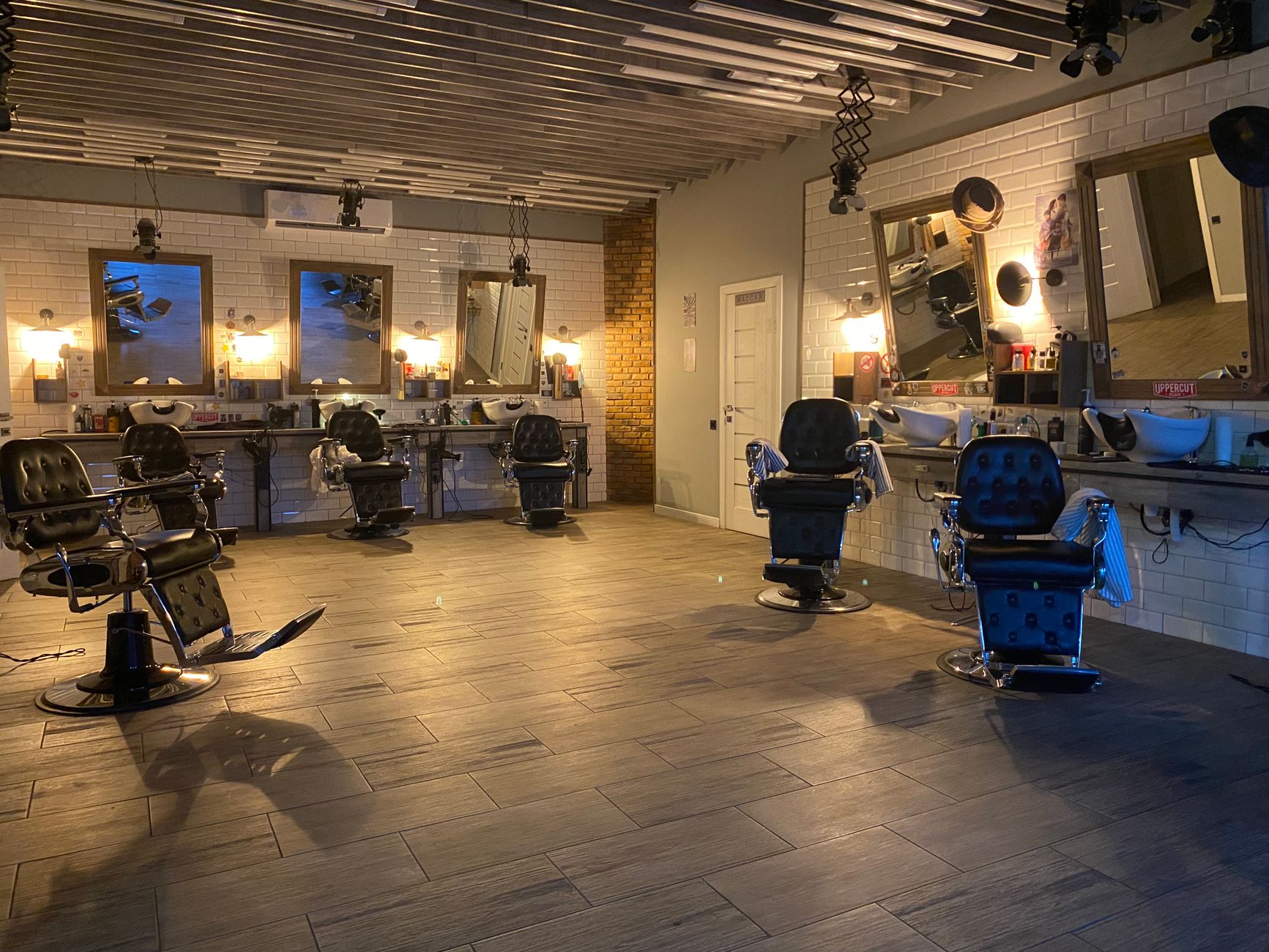 Spacious and stylish hair salon featuring empty barber chairs, mirrors, and elegant lighting.