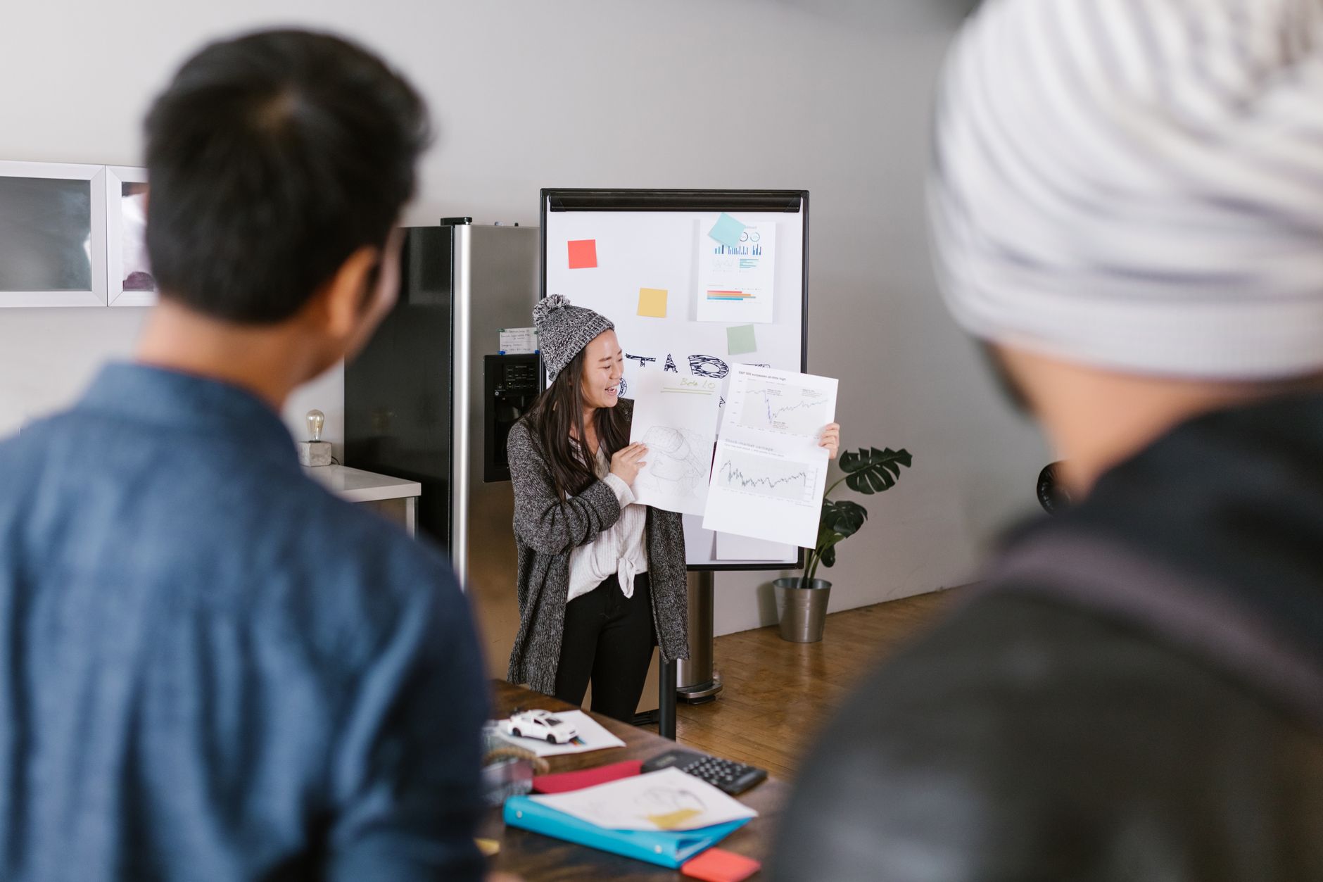 A team of young adults collaborates on a presentation, showcasing ideas with graphs in a modern office setting.