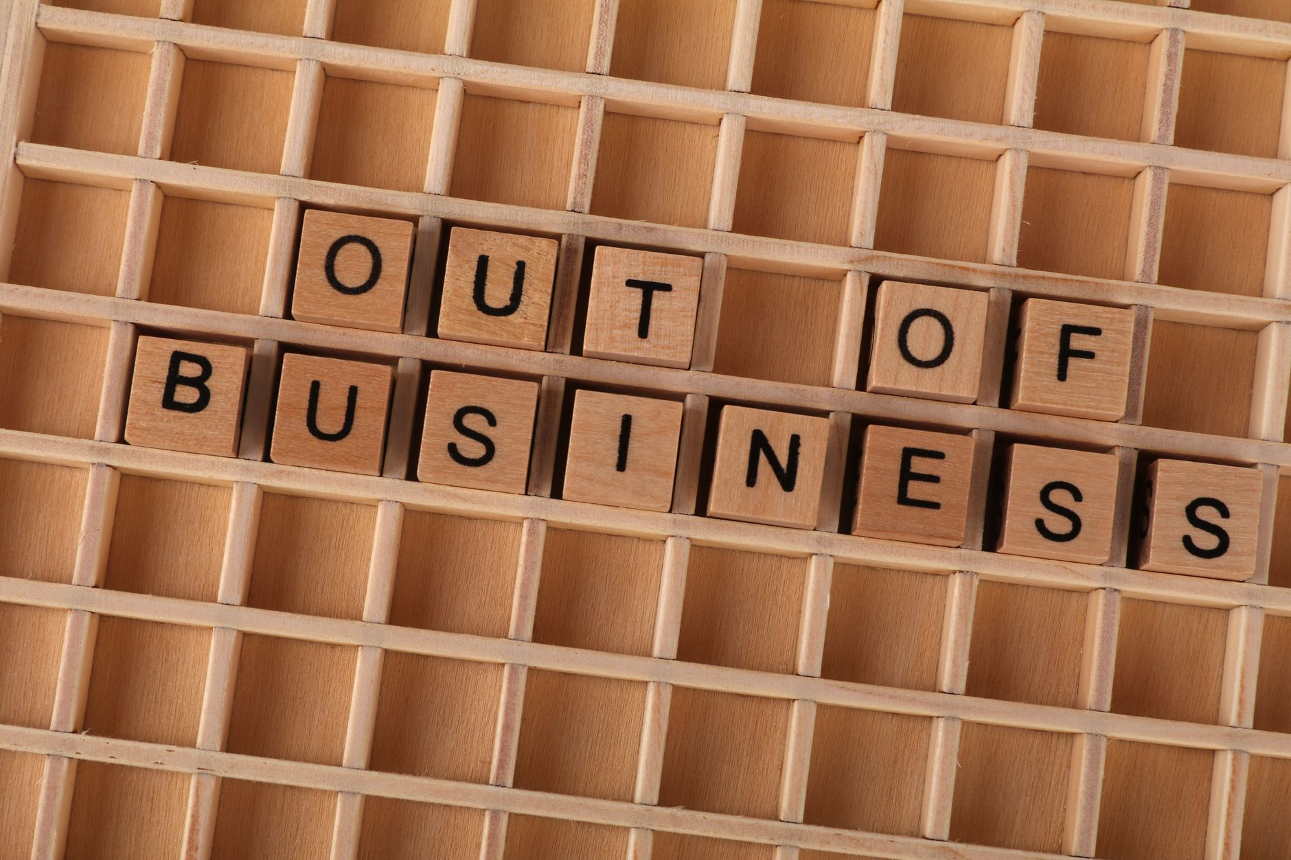 Wooden blocks spelling out 'Out Of Business' symbolize closure or economic downturn.