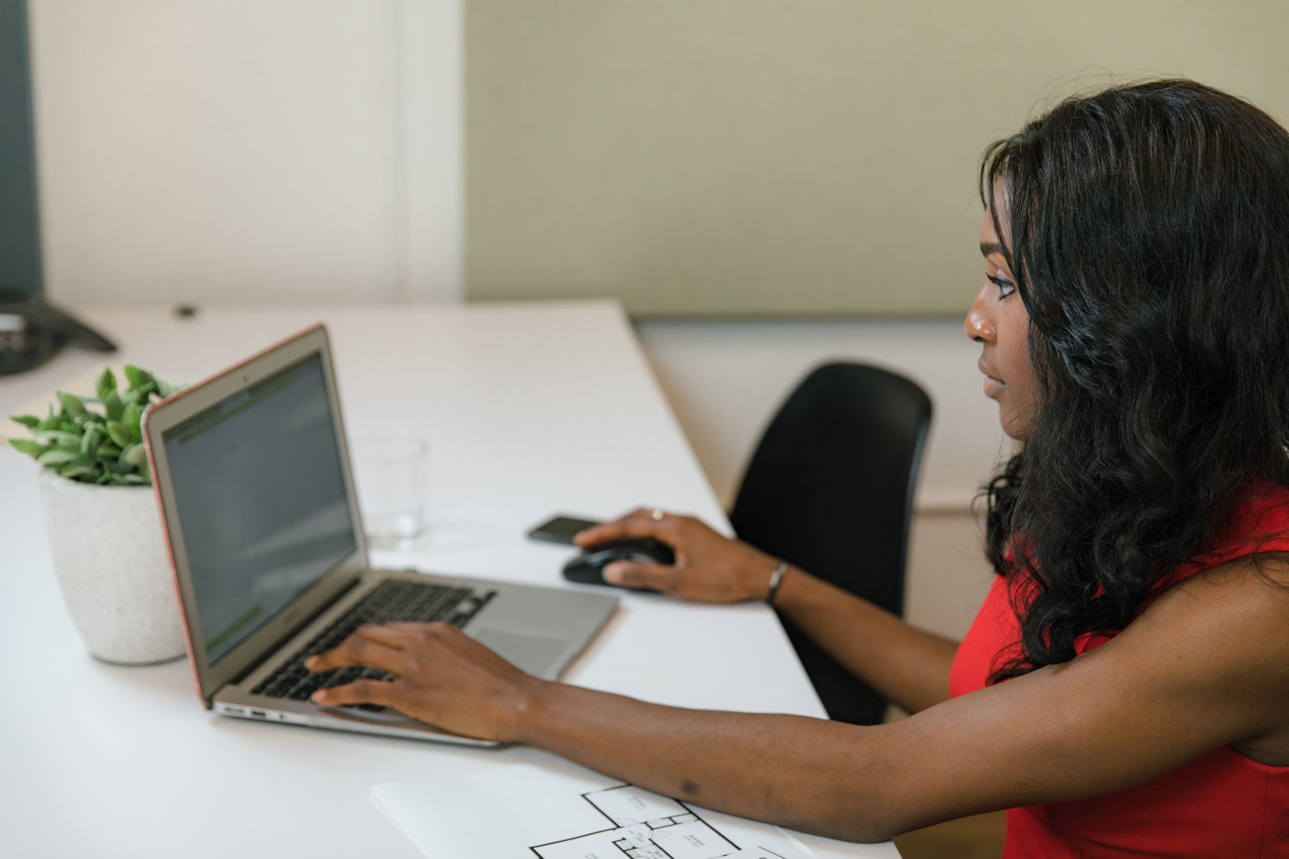 Professional woman working on a laptop at a modern office desk.