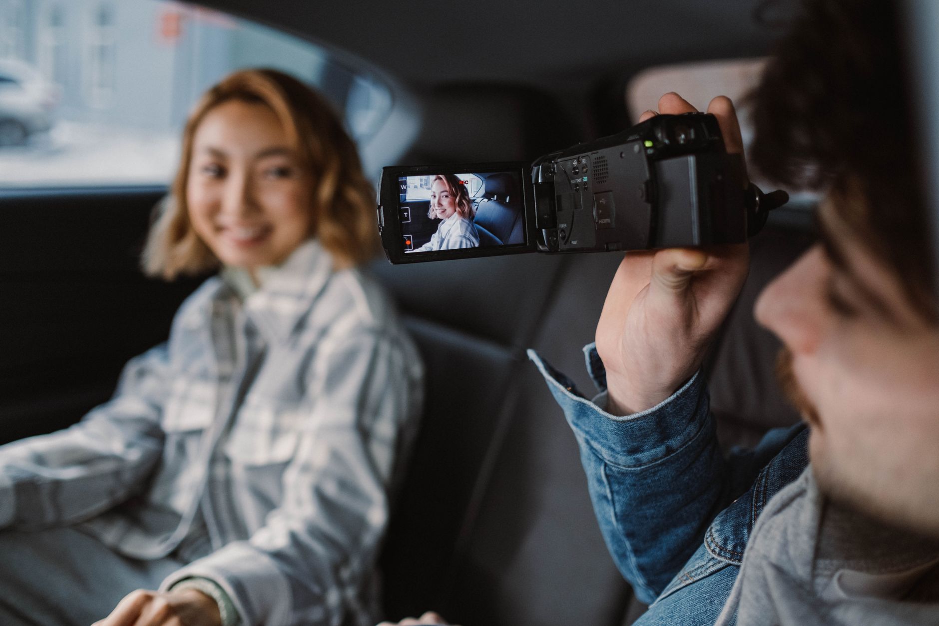 Couple filming each other in car, enjoying a romantic moment with a camcorder.