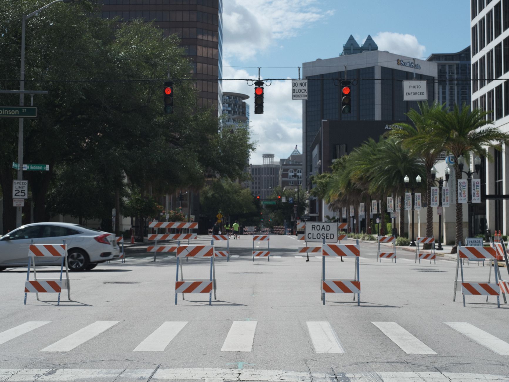 A downtown city intersection with road closures, traffic lights, and tall buildings.