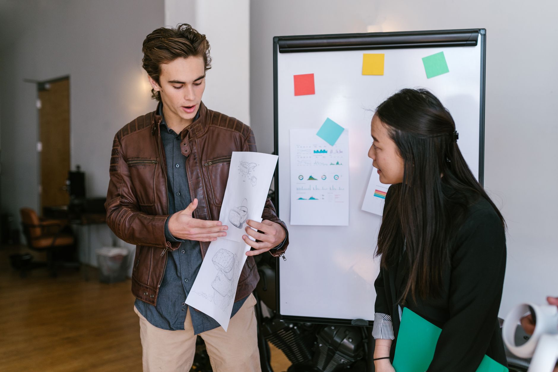 Two young entrepreneurs discussing plans in a modern office setting.