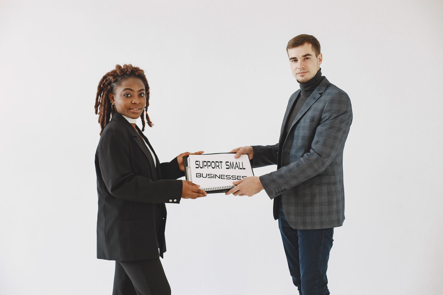 Two diverse business professionals promoting small business support with a sign.