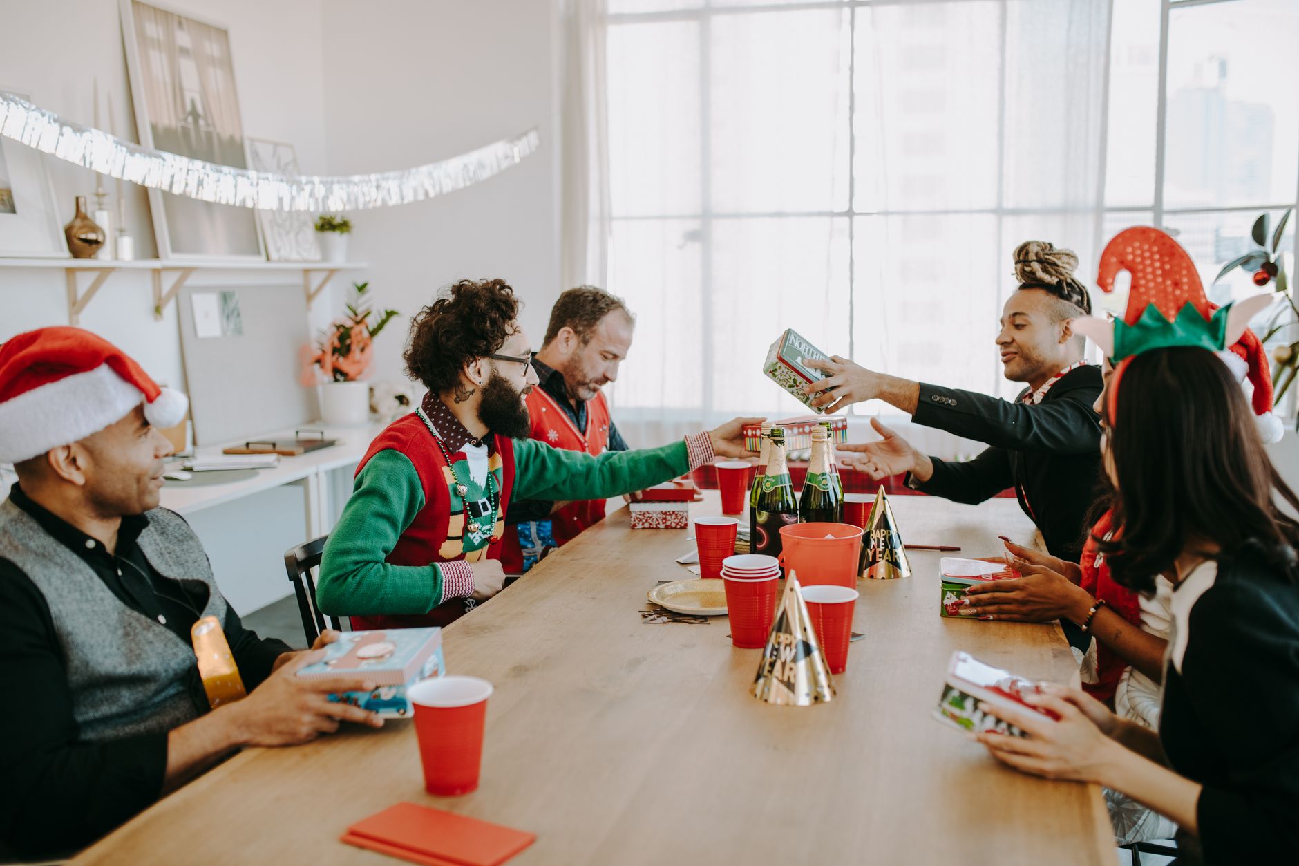 Diverse colleagues exchange gifts during a lively Christmas office party, celebrating the festive season with joy.